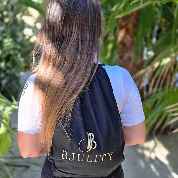 Frau Mit einem schwarzen Stoffbeutelrücksack mit goldenem BJULITY Logo